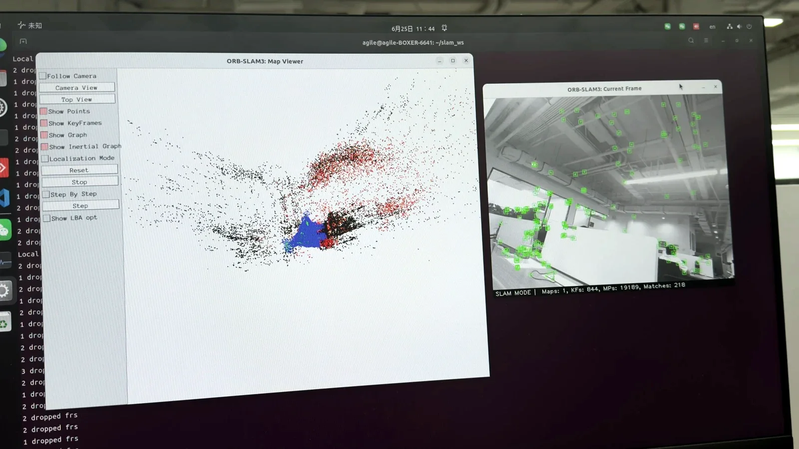 ORB-SLAM3 running on a monitor: a sparse map of red and black points beside the current camera frame with tracked features