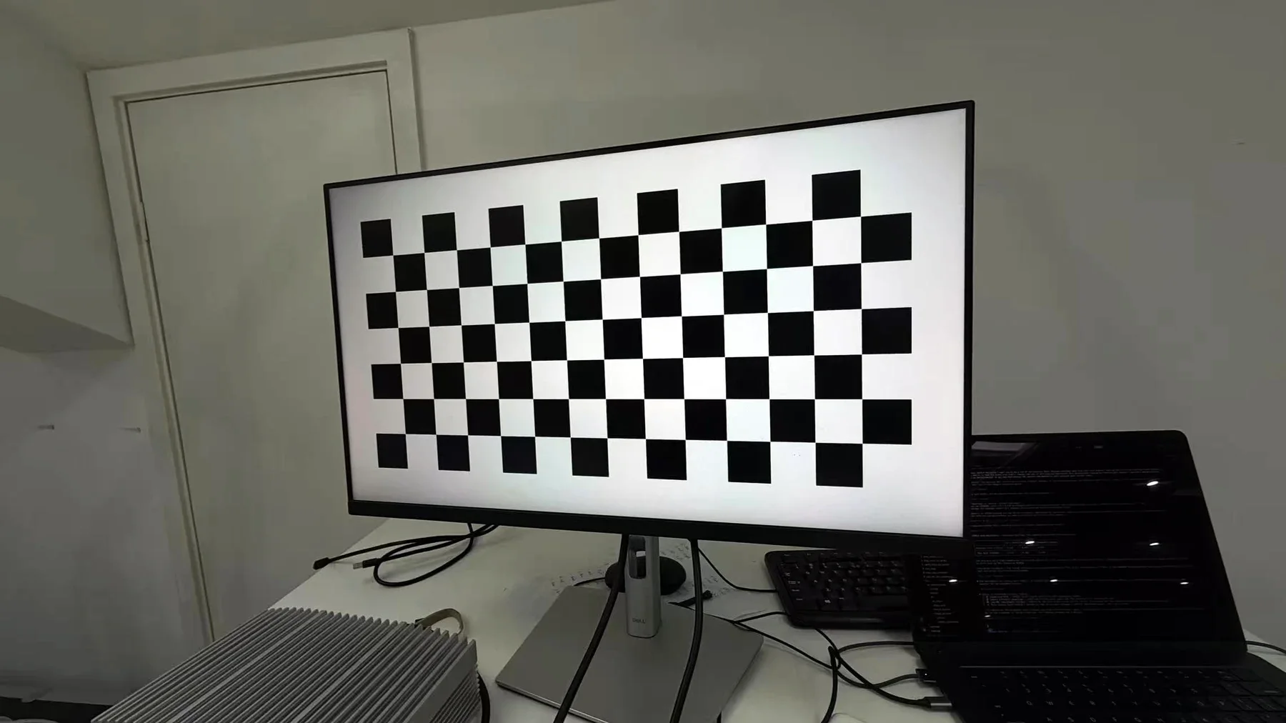 A checkerboard filling a Dell monitor, used as the calibration target